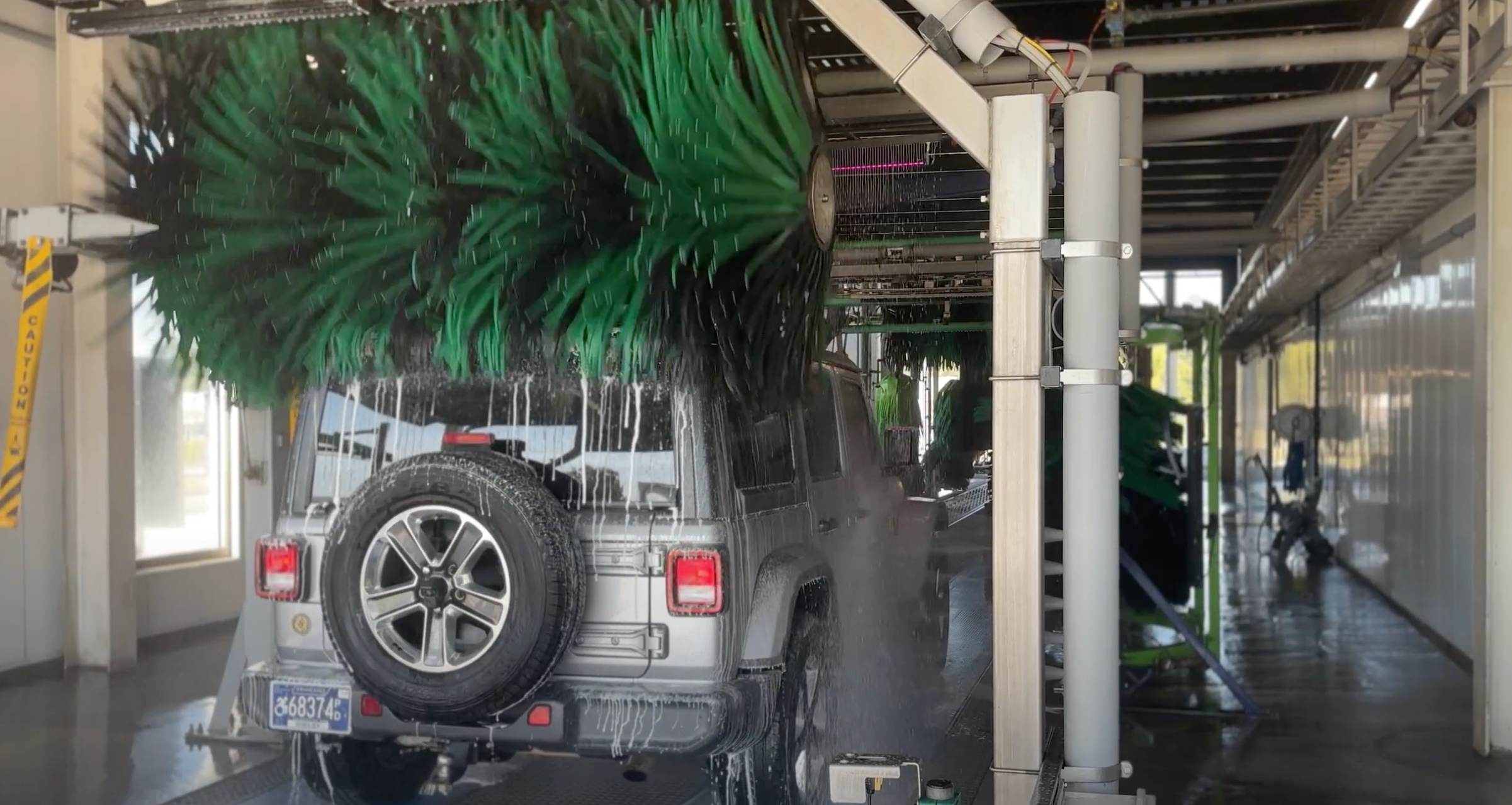 Jeep going through car wash tunnel with green brushes