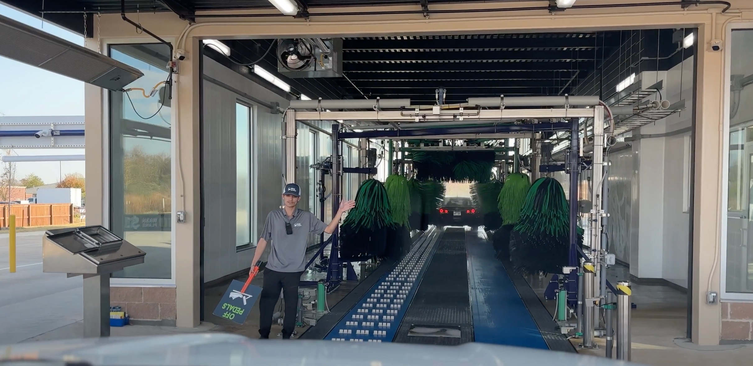 Car wash tunnel interior with green brushes and employee